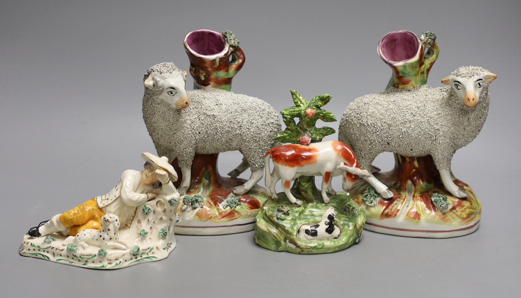 A pair of Staffordshire sheep spill vases, 19 cm high, a similar cow group and a recumbent man and dog